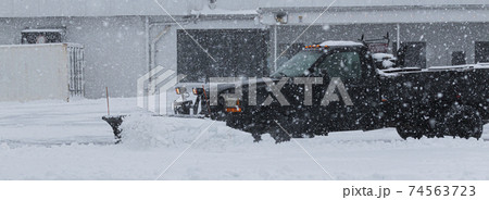 Private contractor plowing parking lot during a blizzard 74563723