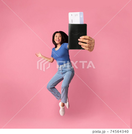 Asian woman holding passport with boarding pass and jumping Asian woman holding passport with boarding pass and jumping 74564340