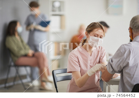 Female Nurse Vaccinating Senior Man 74564452