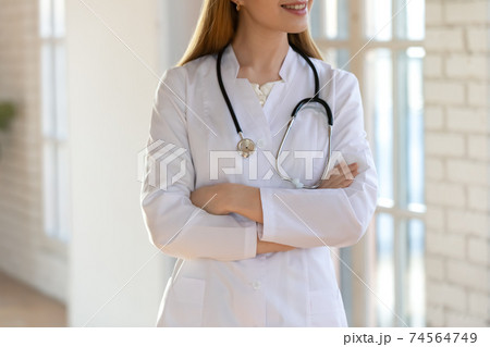Close up smiling young female doctor standing with folded arms. 74564749