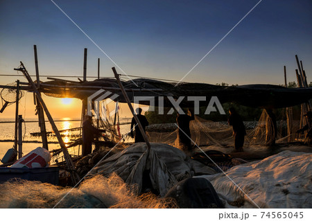 fishermen pulling fishing nets at sunset, 74565045
