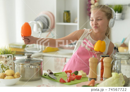 Cute happy girl coocking on kitchen and listening to music Cute happy girl coocking on kitchen and listening to music 74567722