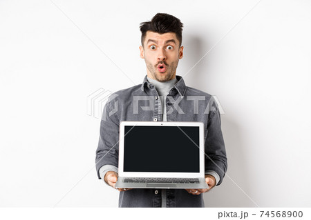 Excited man demostrated empty laptop screen, say wow and look at camera amazed, checking out online offer, showing webpage, standing on white background Excited man demostrated empty laptop screen, say wow and look at camera amazed, checking out online offer, showing webpage, standing on white background 74568900