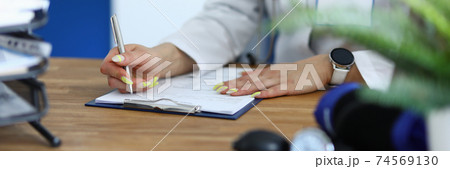 Female doctor holds pen in her hand and makes notes in medical documents Female doctor holds pen in her hand and makes notes in medical documents 74569130