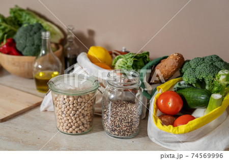 Eco freindly cotton bags with food products and and glass stuff on kitchen table 74569996