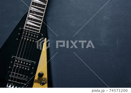 Black V shape electric guitar on dark grunge background. Black V shape electric guitar on dark grunge background. 74571200