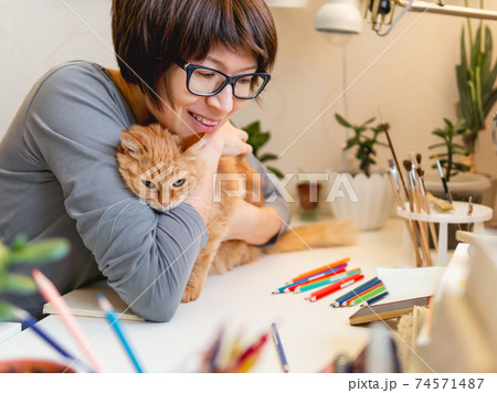Woman with short hair cut hugs cute ginger cat. Fluffy pet and artist. Calming hobby, anti stress leisure. Woman with short hair cut hugs cute ginger cat. Fluffy pet and artist. Calming hobby, anti stress leisure. 74571487