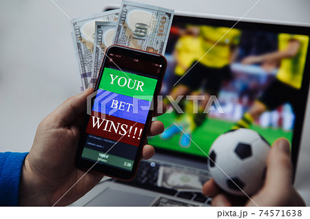 Smartphone with victory message and male's hand with soccer ball. Sport and betting concept Smartphone with victory message and male's hand with soccer ball. Sport and betting concept 74571638
