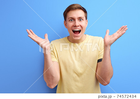 happy caucasian man rejoices and celebrating winning on blue background 74572434