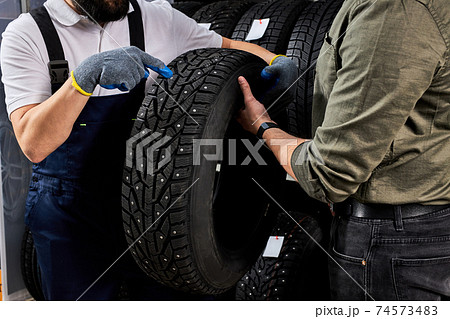 handsome caucasian salesman of tires talking about characteristic of product 74573483