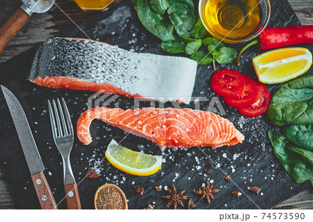 Raw salmon fillet and ingredients for cooking on a dark background Raw salmon fillet and ingredients for cooking on a dark background 74573590