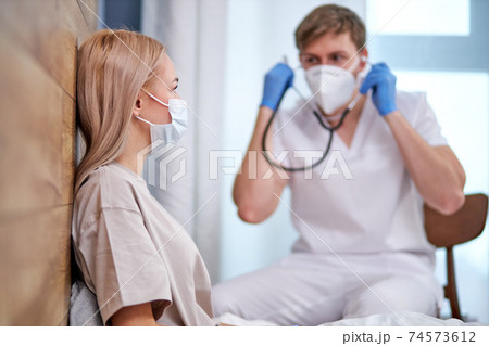 male doctor is going to examine sick patient lying on bed 74573612