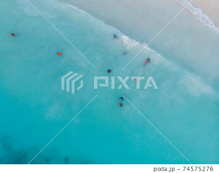 Aerial Drone Shot of Black local African Kids swimming in Turquoise Water of Indian Ocean at Zanzibar island, Nungwi Aerial Drone Shot of Black local African Kids swimming in Turquoise Water of Indian Ocean at Zanzibar island, Nungwi 74575276