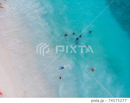 Aerial Drone Shot of Black local African Kids swimming in Turquoise Water of Indian Ocean at Zanzibar island, Nungwi 74575277