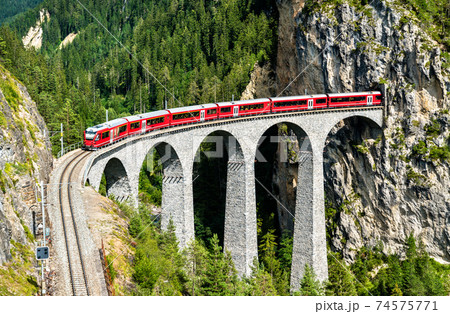 Passenger train crossing the Landwasser Viaduct in Switzerland 74575771