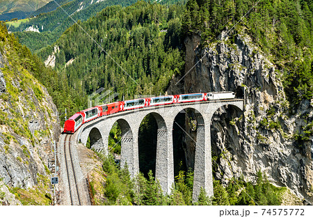 Passenger train crossing the Landwasser Viaduct in Switzerland 74575772