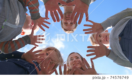 A friendly large family makes a circle shape out of the palms of their hands. 74576749