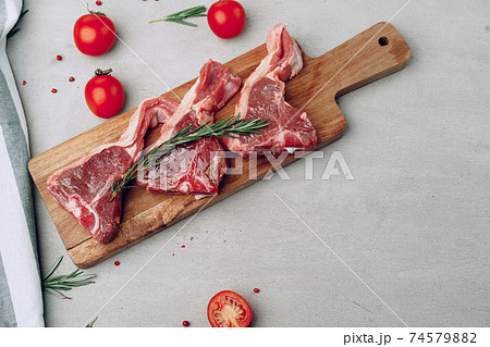 Raw t-bone steak on wooden cutting board on wooden table 74579882