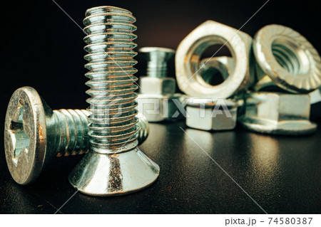 Metal screws and nuts on black background Metal screws and nuts on black background 74580387