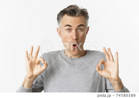 Close-up of impressed middle-aged guy, showing okay signs in approval, like something good, recommending product, standing over white background 74580389