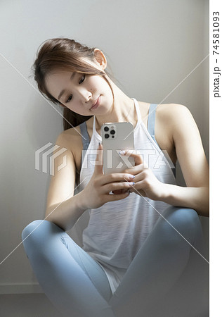 スポーツウェアでスマホを見る女性 スポーツウェアでスマホを見る女性 74581093