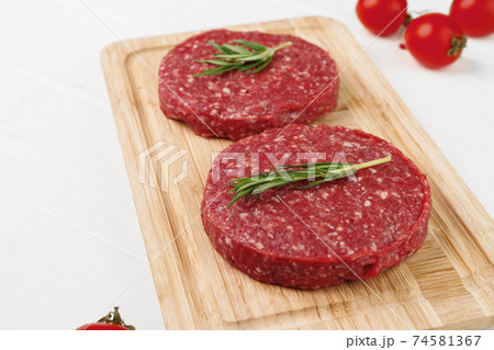 Two raw beef burger patties on wooden board Two raw beef burger patties on wooden board 74581367