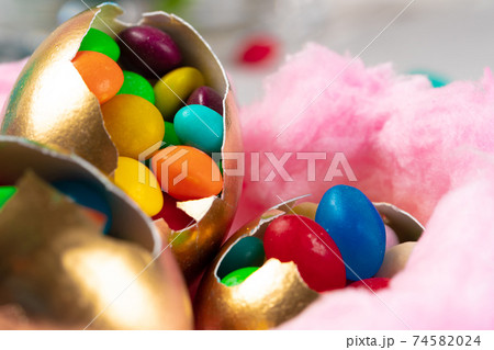 Egg shell with colorful candies inside in a decorative Easter nest Egg shell with colorful candies inside in a decorative Easter nest 74582024