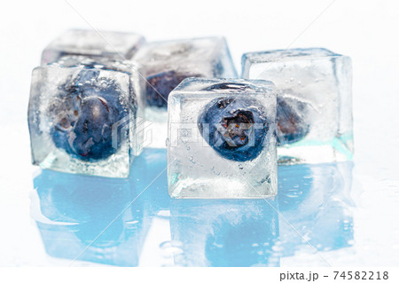 Frozen berries in ice cubes on pink Frozen berries in ice cubes on pink 74582218