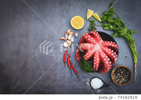 Fresh squid octopus cuttlefish dinner restaurant, Octopus food salad vegetable with garlic lemon chili salt coriander parsley and pepper on black plate for boiled cooked seafood. 74582910