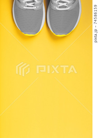 Sports gray sneakers on a yellow background - sport concept, free space. Sports gray sneakers on a yellow background - sport concept, free space. 74586159