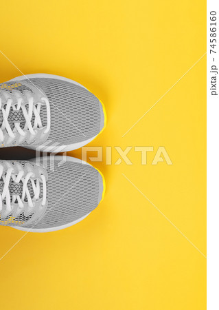 Sports gray sneakers on a yellow background - sport concept, free space. Sports gray sneakers on a yellow background - sport concept, free space. 74586160