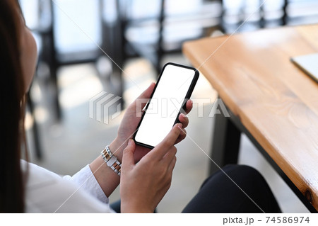 Cropped shot of young female entrepreneur sitting at her workplace and using mobile phone. 74586974