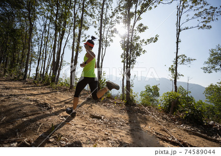 Young woman trail runner running in sunrise tropical forest 74589044