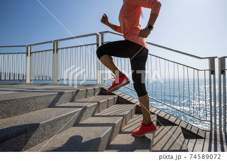 Healthy lifestyle fitness sports woman runner running up stairs on seaside trail 74589072
