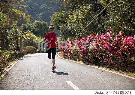 Fitness woman runner running on winter park trail 74589073