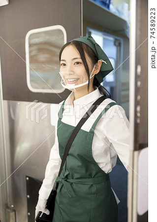 スイングドアを開けてバックヤードから出てくるマウスシールドをした女性店員 74589223