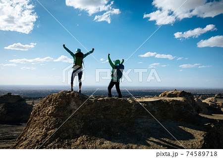 Two women backpackers hiking on sand desert 74589718