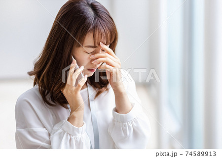 スマホを耳にあて悩ましい表情をみせる女性 74589913