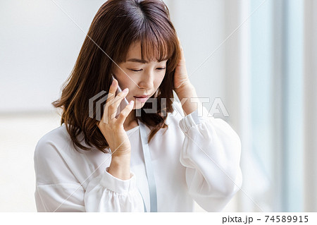 スマホを耳にあて悩ましい表情をみせる女性 74589915