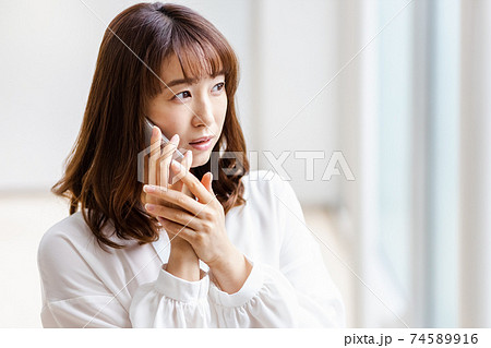 スマホを耳にあて悩ましい表情をみせる女性 スマホを耳にあて悩ましい表情をみせる女性 74589916