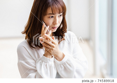 スマホを耳にあて悩ましい表情をみせる女性 スマホを耳にあて悩ましい表情をみせる女性 74589918