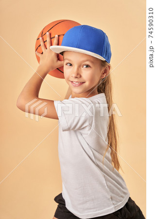 Adorable joyful girl in cap plying basketball Adorable joyful girl in cap plying basketball 74590310