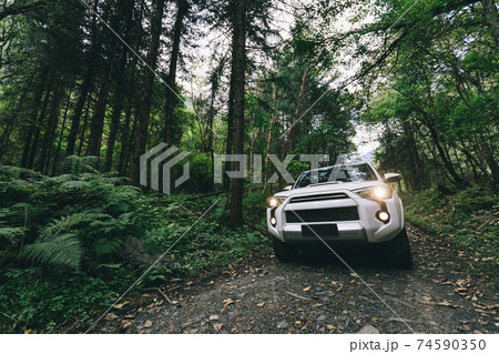 Driving offroad car on trail in high altitude forest mountain Driving offroad car on trail in high altitude forest mountain 74590350