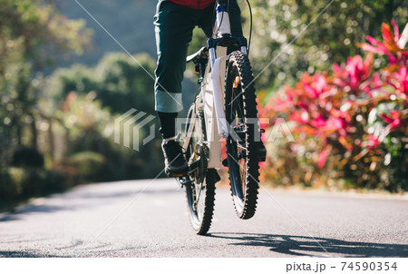 Woman riding a bike on tropical park trail in spring 74590354