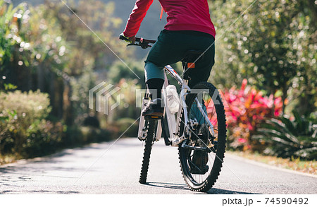 Woman riding a bike on tropical park trail in spring 74590492
