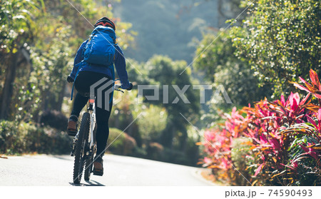 Woman riding a bike on tropical park trail in spring 74590493