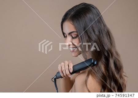 Woman with beautiful long hair and flat iron. 74591347