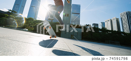 Asian woman skateboarder skateboarding in modern city Asian woman skateboarder skateboarding in modern city 74591798