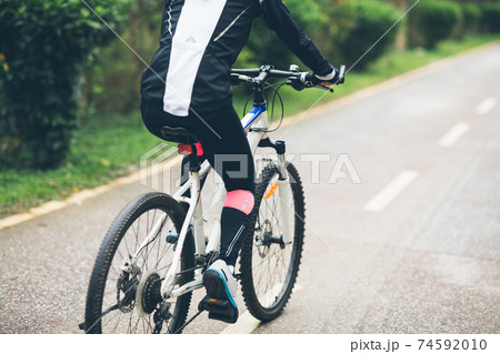 Woman cyclist riding a bike on tropical park trail in spring 74592010