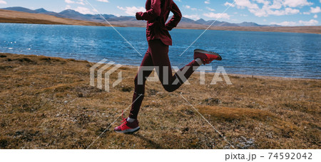 Woman trail runner cross country running on winter lakeside 74592042